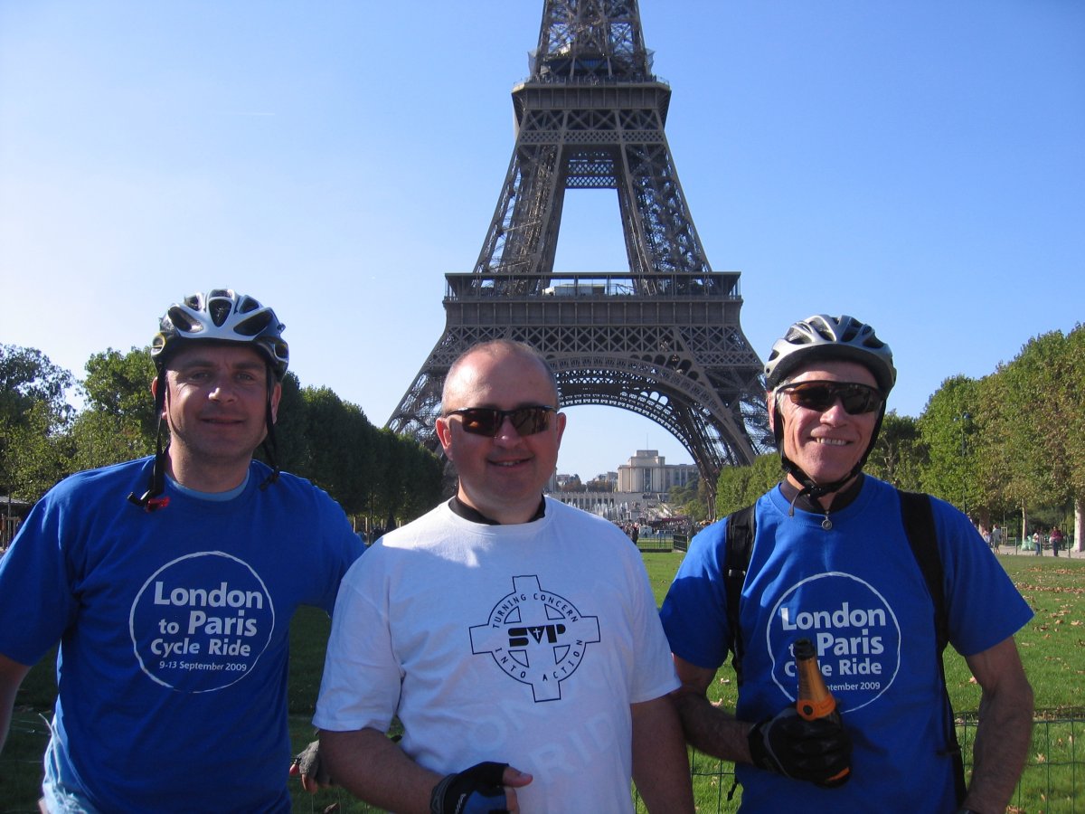 Three men in front of Eiffel tower with Paris bike ride t-shirts