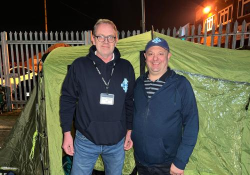 Image of two men infront of tent